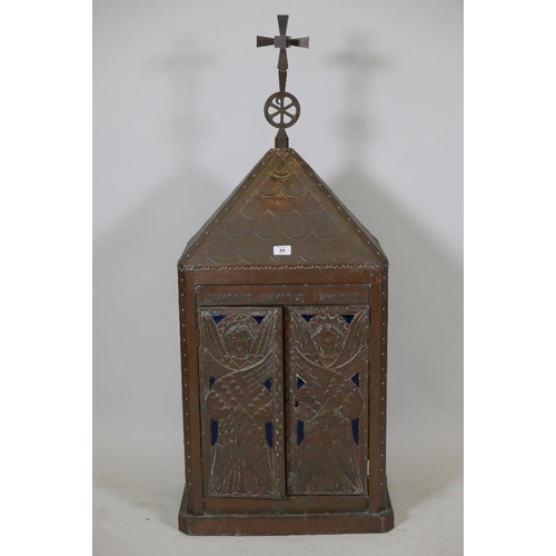 89 - A Continental copper shrine with two doors with raised decoration of angels opening to reveal quilte... 