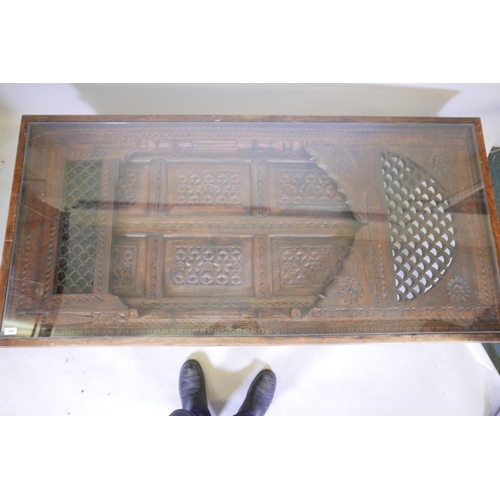 1204 - An Indian carved hardwood table with glass top and two frieze drawers, raised on turned supports