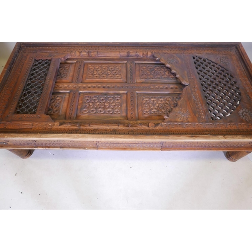 1204 - An Indian carved hardwood table with glass top and two frieze drawers, raised on turned supports