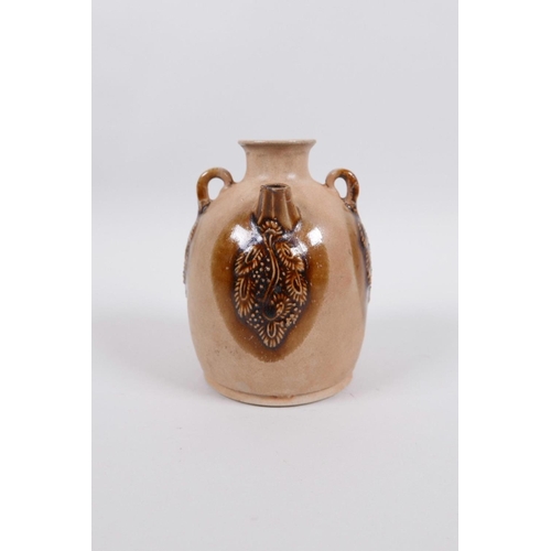 65 - A Chinese pottery wine pourer with two lug handles and raised glazed fruiting vine decoration, 4½