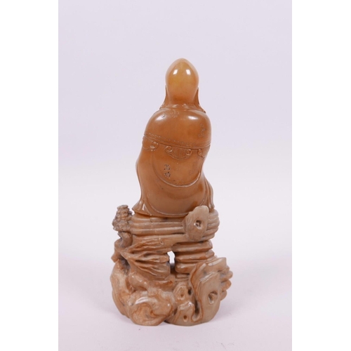 71 - A Chinese natural amber soapstone carving of Shao Lao seated on a rocky outcrop, 5½