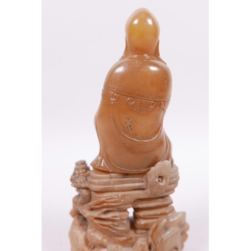 71 - A Chinese natural amber soapstone carving of Shao Lao seated on a rocky outcrop, 5½