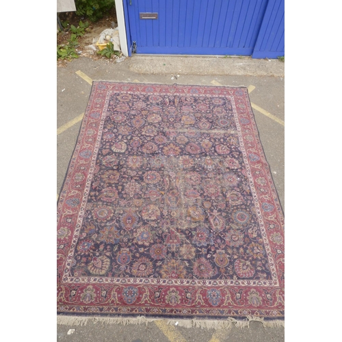 1206 - A large blue ground Persian wool rug with stylised floral decoration, and a red border (worn), 108