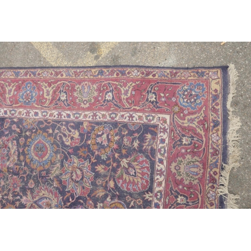 1206 - A large blue ground Persian wool rug with stylised floral decoration, and a red border (worn), 108