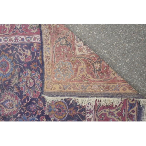 1206 - A large blue ground Persian wool rug with stylised floral decoration, and a red border (worn), 108