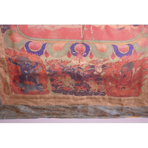 24 - A Sino-Tibetan printed thangka depicting a wrathful deity, with a silk surround, 30½