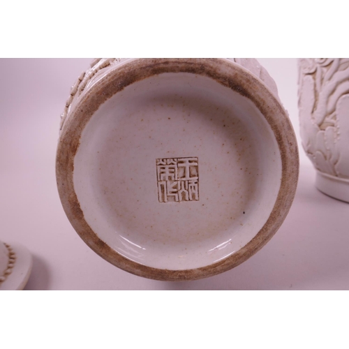 44 - A pair of Chinese white ground pottery jar and covers with raised moulded dragon decoration, impress... 