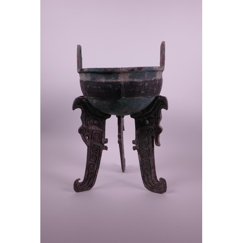 269 - A Chinese bronze ding on tripod feet with archaic decoration and two handles, inscribed to base, 14