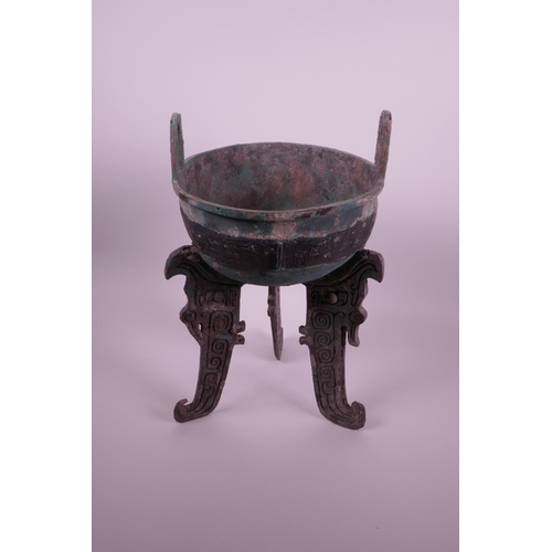 269 - A Chinese bronze ding on tripod feet with archaic decoration and two handles, inscribed to base, 14