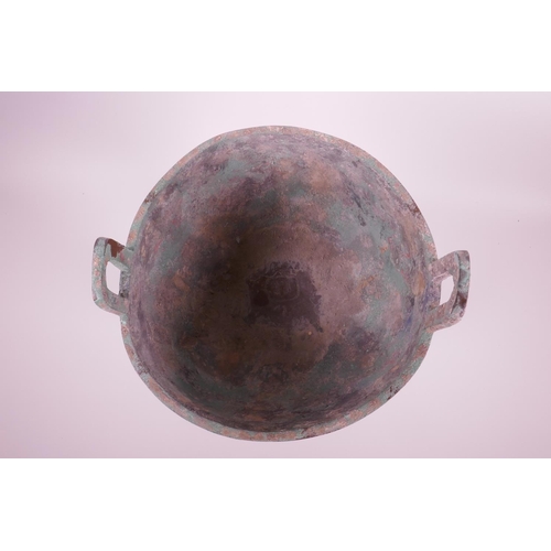 269 - A Chinese bronze ding on tripod feet with archaic decoration and two handles, inscribed to base, 14