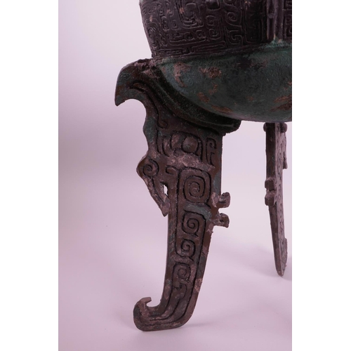 269 - A Chinese bronze ding on tripod feet with archaic decoration and two handles, inscribed to base, 14