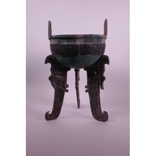 269 - A Chinese bronze ding on tripod feet with archaic decoration and two handles, inscribed to base, 14