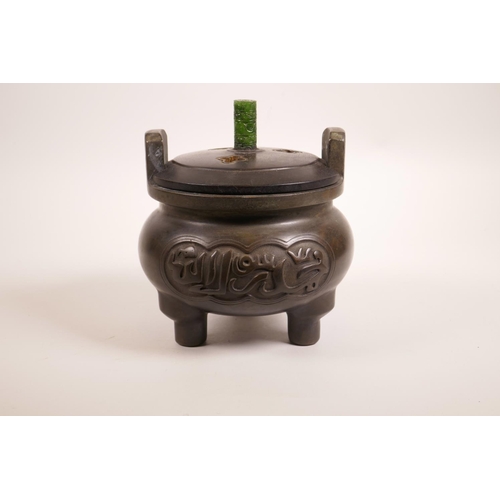 64 - A Chinese bronze censer on tripod feet with two handles, turned hardwood lid, carved green jade knop... 