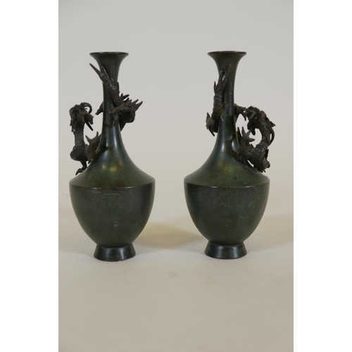 67 - A pair of Japanese patinated bronze vases with raised decoration of climbing dragons, signed, 8