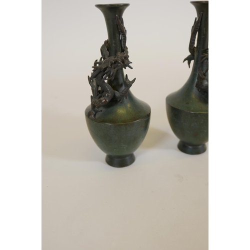 67 - A pair of Japanese patinated bronze vases with raised decoration of climbing dragons, signed, 8