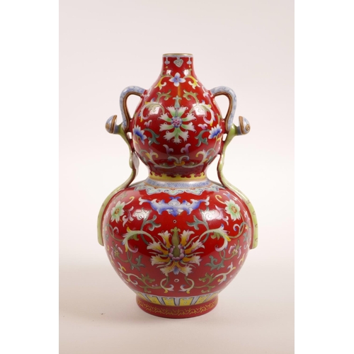 78 - A Chinese red ground porcelain vase with two handles and polychrome lotus flower decoration, 4 chara... 