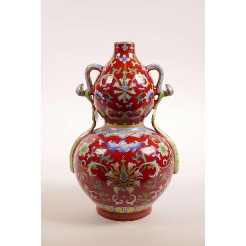 78 - A Chinese red ground porcelain vase with two handles and polychrome lotus flower decoration, 4 chara... 