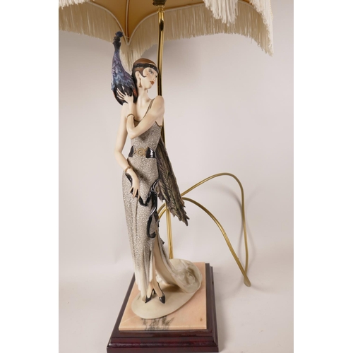 32 - An Art Deco style table lamp in the form of a lady with a peacock on her shoulder, with single brass... 