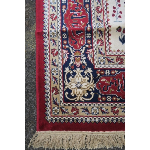 1135 - A red and ivory ground Kashmir carpet, decorated with a traditional hunting scene