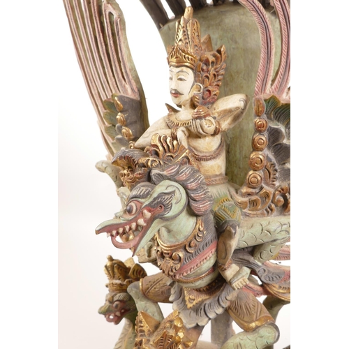 12 - A Balinese carved and painted wood figure of Vishnu riding Garuda, losses, 20½