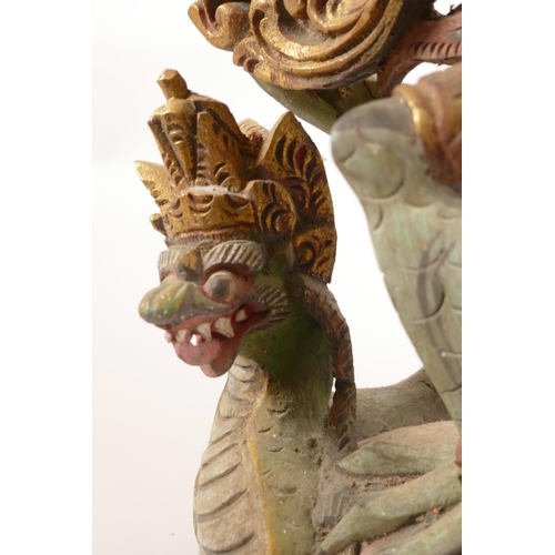 12 - A Balinese carved and painted wood figure of Vishnu riding Garuda, losses, 20½