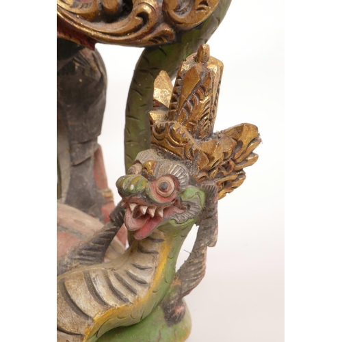 12 - A Balinese carved and painted wood figure of Vishnu riding Garuda, losses, 20½