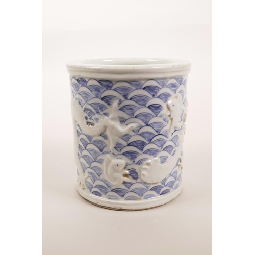 5 - A Chinese blue and white porcelain brush pot with raised decoration of a dragon catching carp, impre... 