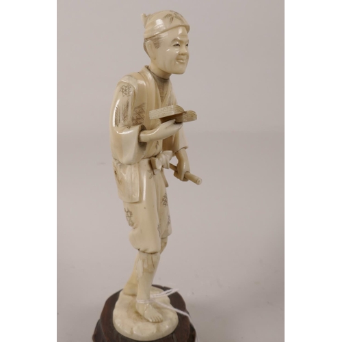 71 - A Japanese Meiji period carved ivory figurine of a man with book and cane, of sectional construction... 