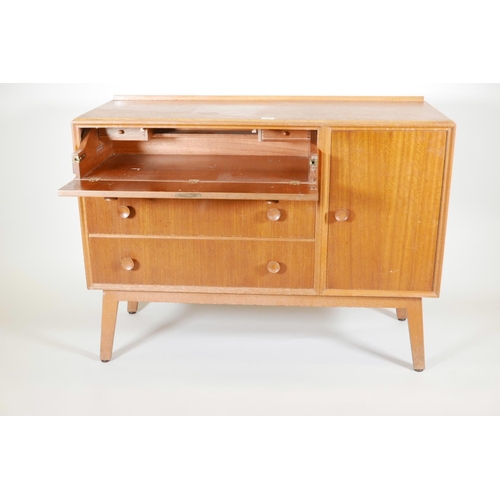 1131 - A mid C20th teak side cabinet with single cupboard and fall front drawer over two drawers, probably ... 