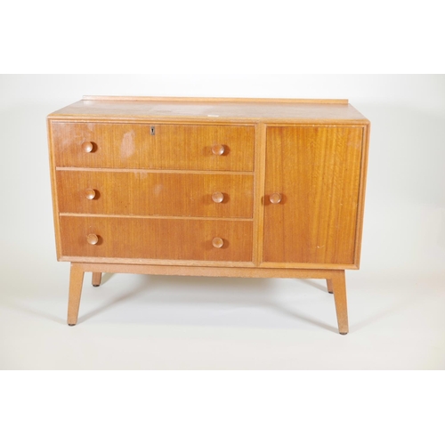 1131 - A mid C20th teak side cabinet with single cupboard and fall front drawer over two drawers, probably ... 