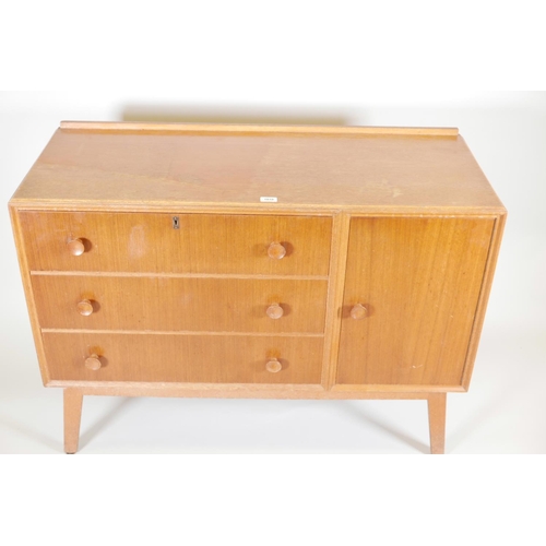 1131 - A mid C20th teak side cabinet with single cupboard and fall front drawer over two drawers, probably ... 