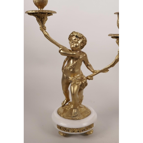 62 - A pair of ormolu two branch candlesticks in the form of putti, on marble bases,  12