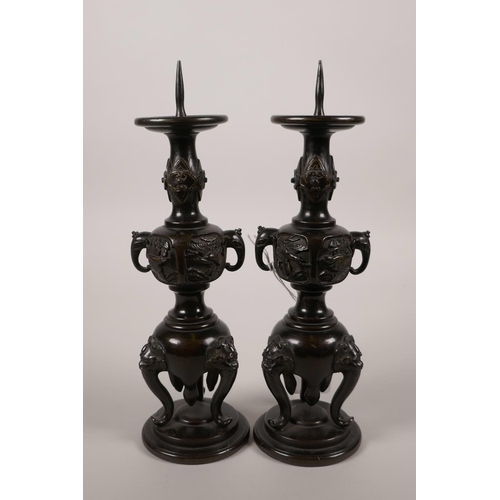 65 - A pair of Japanese bronze candlesticks in the form of vases on stands, 9½