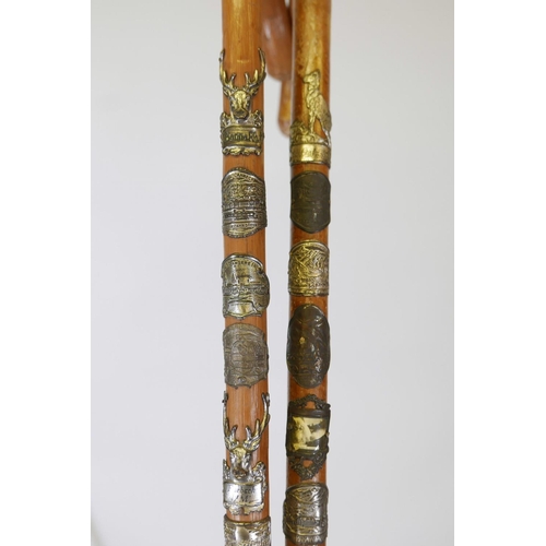 57 - Three hiking canes with associated badges applied to the shafts, together with a hallmarked silver m... 