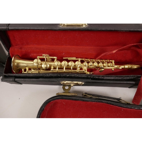 27 - Six novelty miniature musical instruments in fitted cases, tenor and soprano saxophones, euphonium, ... 