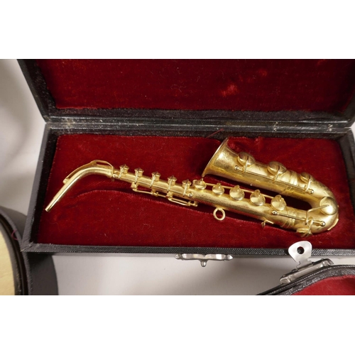 27 - Six novelty miniature musical instruments in fitted cases, tenor and soprano saxophones, euphonium, ... 