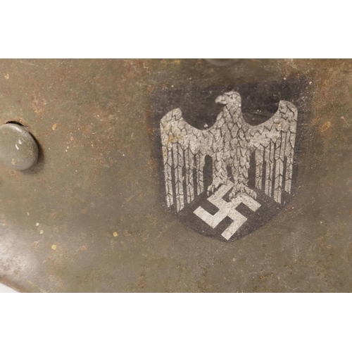 6 - A WWII German steel combat helmet with leather interior, and eagle and swastika decal to side