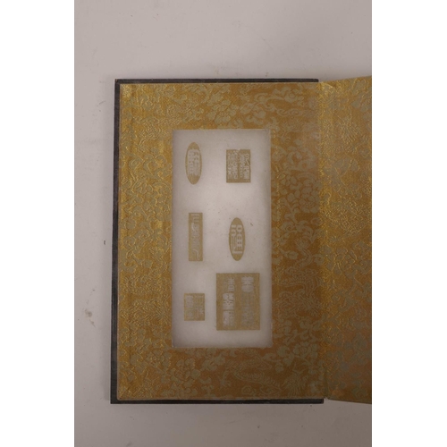 115 - A Chinese wood and silk bound book containing gilt engraved white jade tablets, 6