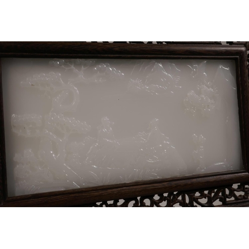 58 - A Chinese white jade table screen in a carved and pierced hardwood frame, the jade tablet decorated ... 