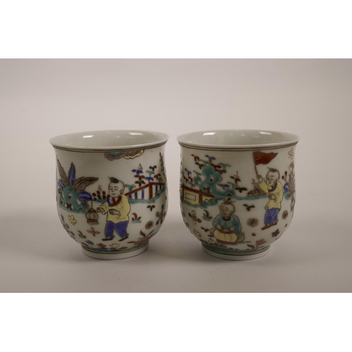 60 - A pair of Chinese polychrome enamelled porcelain tea bowls decorated with boys playing in a garden, ... 