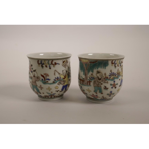 60 - A pair of Chinese polychrome enamelled porcelain tea bowls decorated with boys playing in a garden, ... 