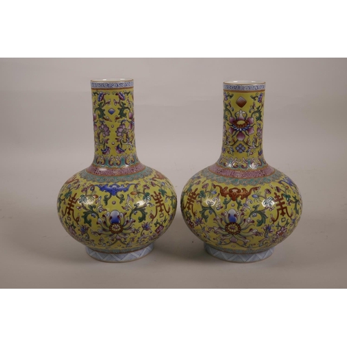 43 - A pair of polychrome porcelain bottle vases with enamelled decoration depicting lotus flowers, bats ... 