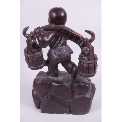 48 - An Oriental carved wood figurine of a boy carrying two baskets on a yoke, 12