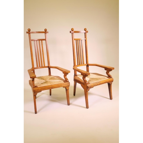 1178 - A pair of Arts and Crafts oak high back elbow chairs with drop in rush seats, 42