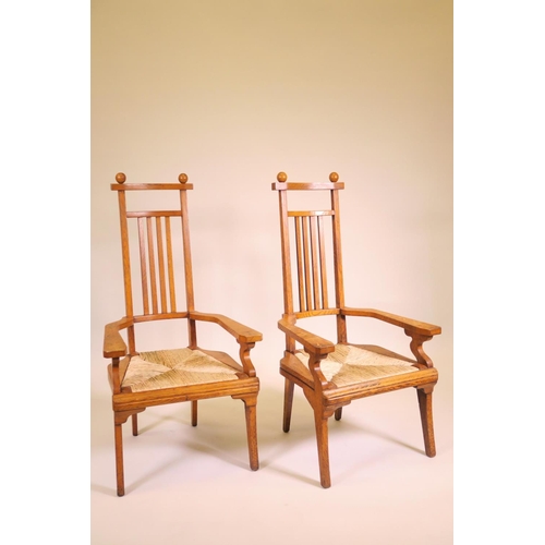 1178 - A pair of Arts and Crafts oak high back elbow chairs with drop in rush seats, 42