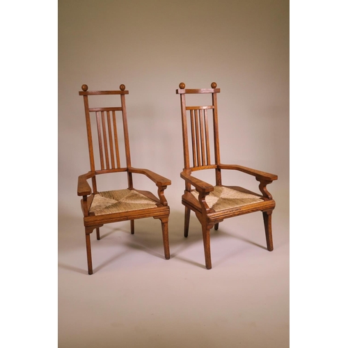 1178 - A pair of Arts and Crafts oak high back elbow chairs with drop in rush seats, 42