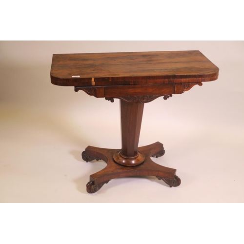 1180 - A Regency rosewood fold over card table on tapered octagonal column and quadraform base on scroll ca... 