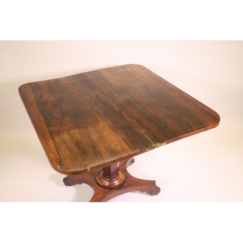 1180 - A Regency rosewood fold over card table on tapered octagonal column and quadraform base on scroll ca... 