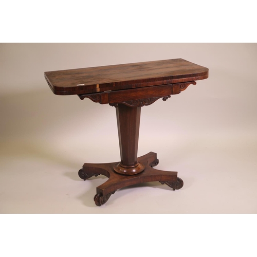 1180 - A Regency rosewood fold over card table on tapered octagonal column and quadraform base on scroll ca... 