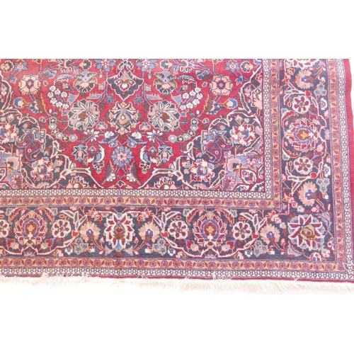 1184 - A vintage Kashan hand knotted wool carpet with central medallion design and blue borders on a red fi... 